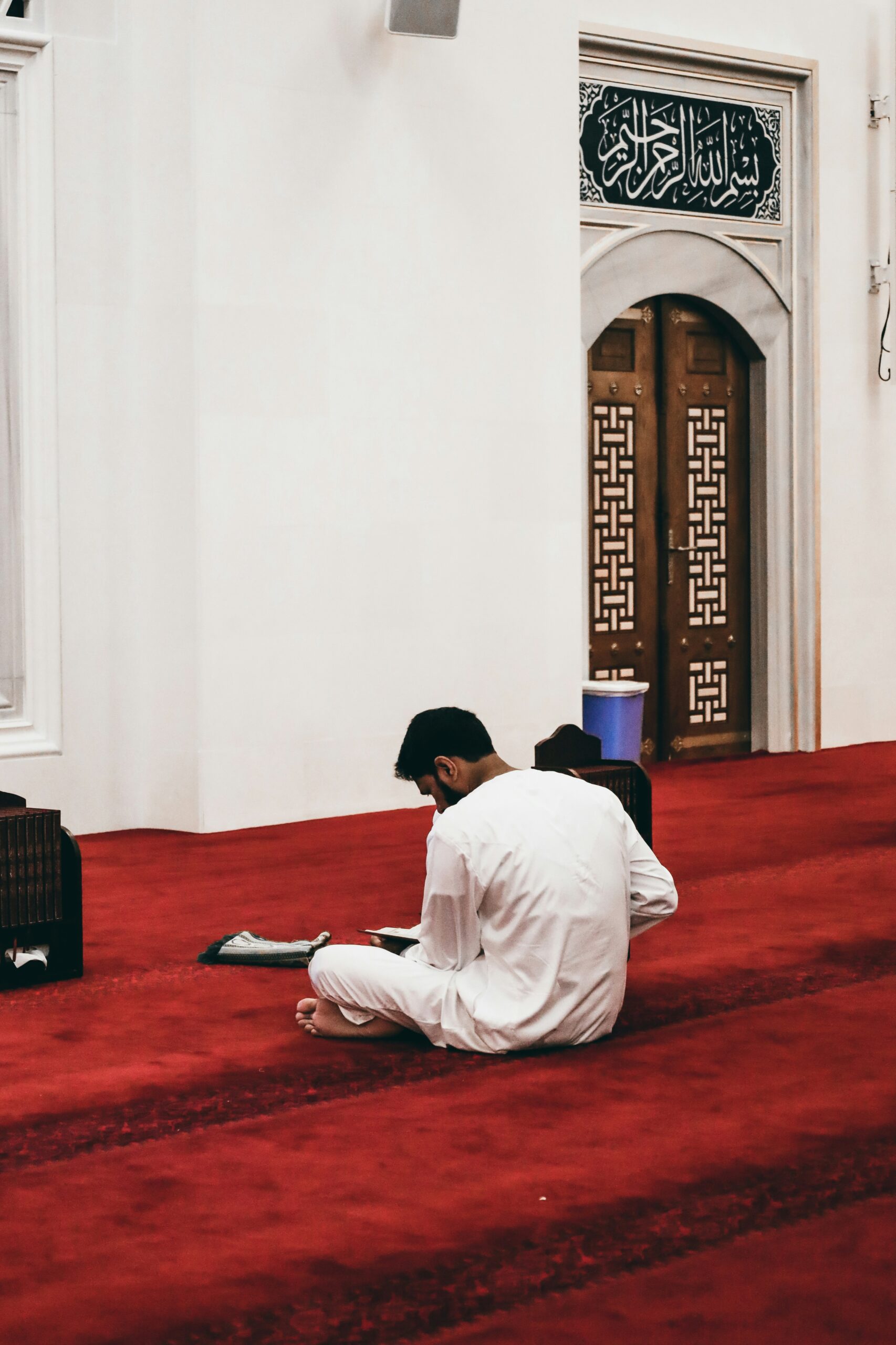 a man sitting on the floor of a mosque reading a book